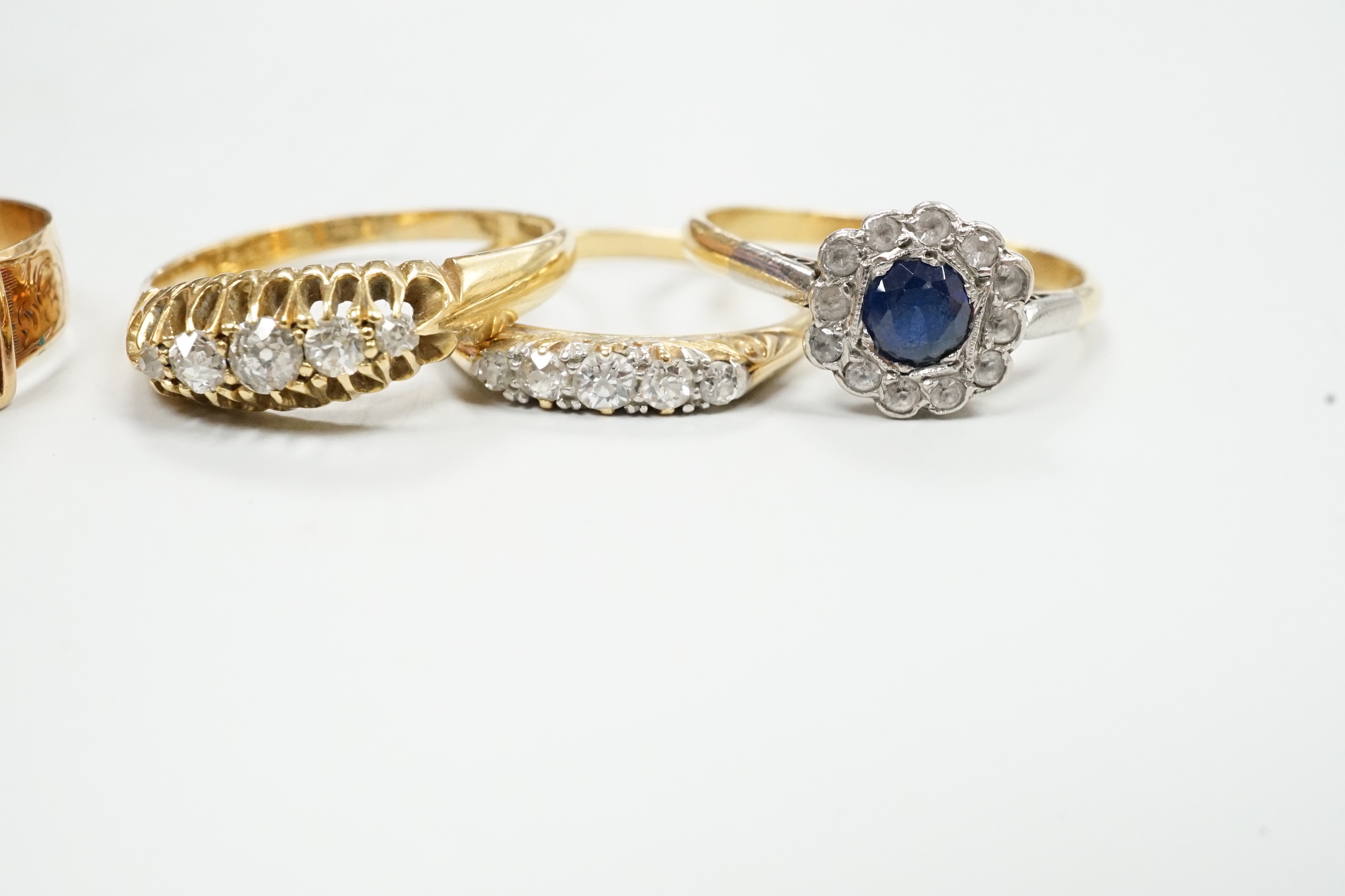 A Victorian 18ct gold and gem set dress ring, size I, three other 18ct and gem set rings and a yellow metal and diamond set buckle ring, gross weight 13.3 grams.